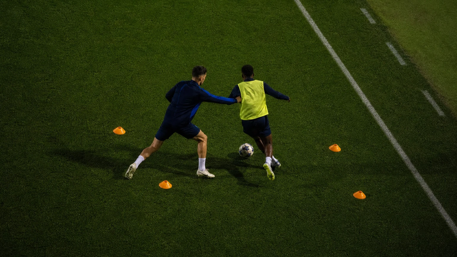a defender steering an attacker towards the sideline, both moving laterally along a coned funnel